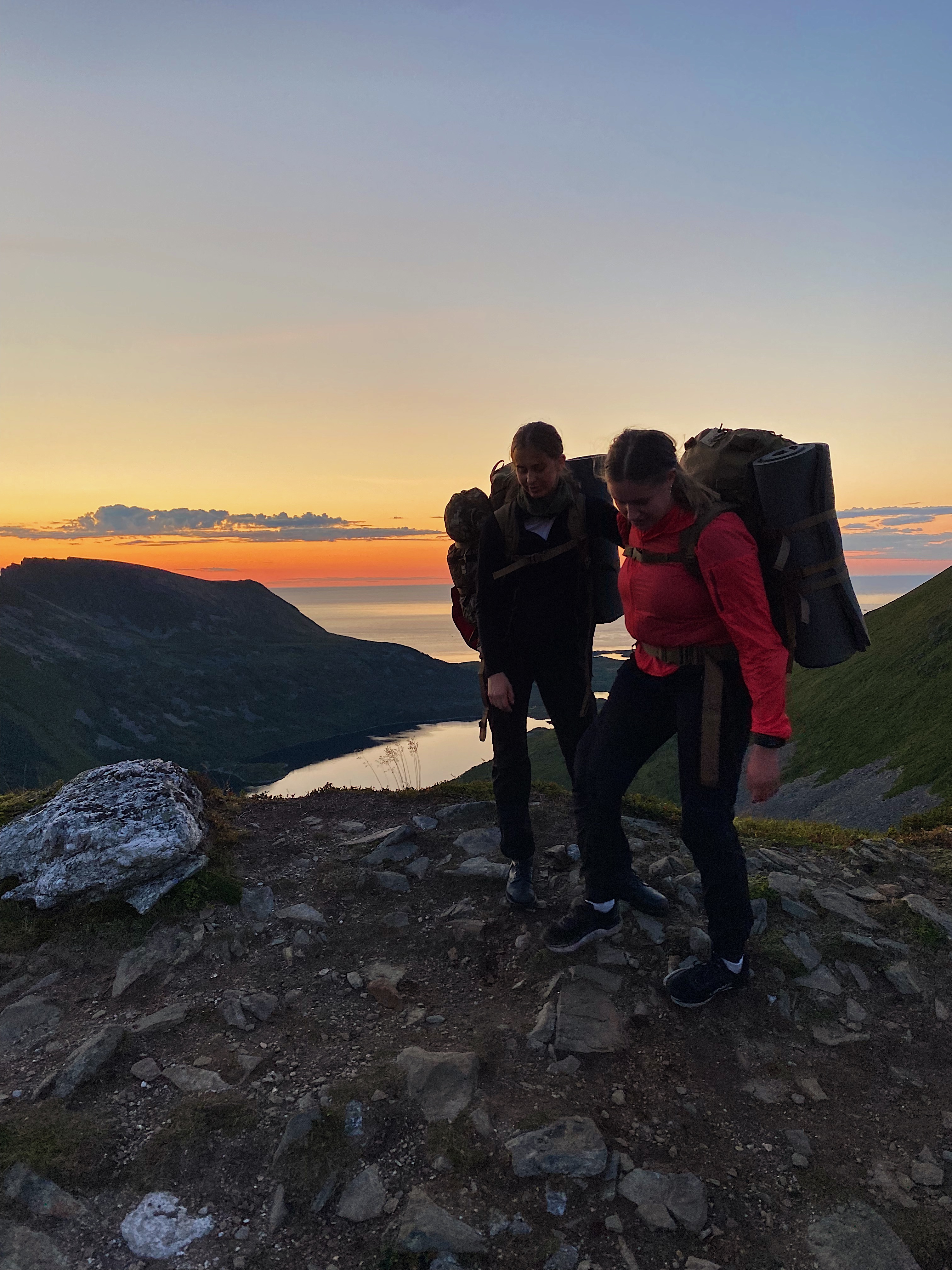 Two hikers on a mountain ridge at sunset